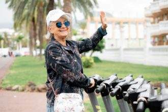 Elderly white-haired woman ready to rent electric scooter for a city tour, sustainable mobility