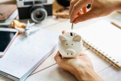 Young traveler holding piggy bank and collecting money and planning a vacation trip